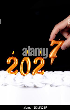 Four golden candles write numbers flame happy new year 2027 hand black background Stock Photo