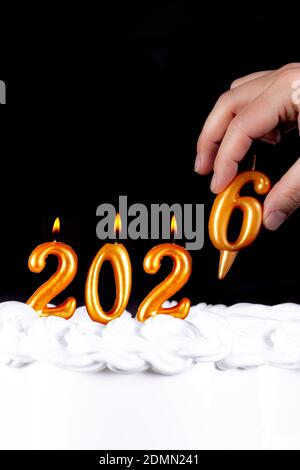 Four golden candles write numbers flame happy new year 2026 hand black background Stock Photo