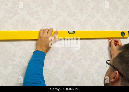 the master makes the markup using a bubble level. DIY Home repairing Stock Photo