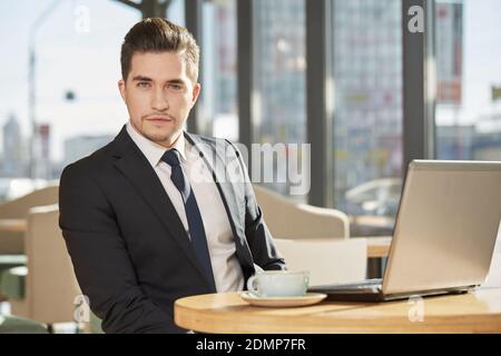 Serious to the bone. Portrait of a handsome young businessman wearing a suit looking to the camera seriously sitting at the local coffee shop Stock Photo