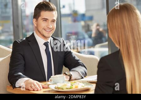 Pleasure to work with you. Cheerful businessman smiling joyfully having a business meeting with his female colleague at the restaurant Stock Photo