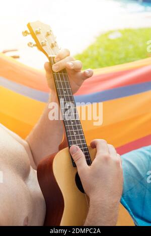 Midsection Of Man Playing Guitar While Sitting In Hammock