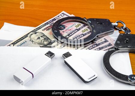 Envelope with an American Dollars Handcuffs and Two USB Drives on the Table closeup Stock Photo
