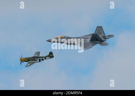 A P-51 Mustang and a F-22 fighters flying in formation at the RIAT air-show in England Stock Photo