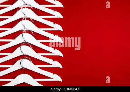 Horizontal color image with a front view of a white hangers on a red background. Sales clothes concept. Stock Photo