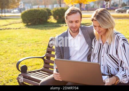Mature businessman discussing project with his female colleague outdoors in the park. Technology, internet concept Stock Photo