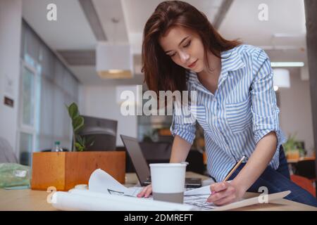 Achieving business goals concept. Low angle shot of a beautiful young female architect sketching at her workplace, copy space. Focused female engineer Stock Photo