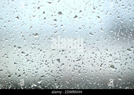 Background with rain droplets on window glass on gloomy autumn day on blur gray background close up Stock Photo