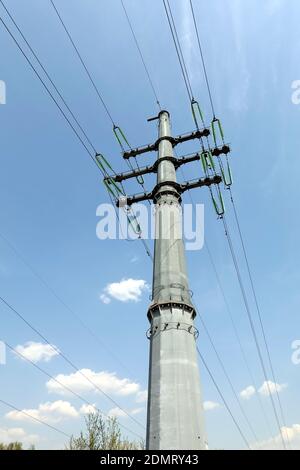 High-voltage strong power line metal prop painted grey with many wires on electrical insulation view from bottom to top close up Stock Photo