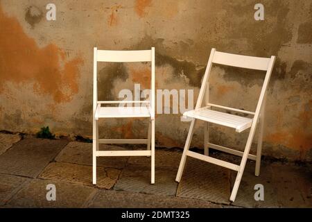 Empty Chairs On Footpath Against Wall
