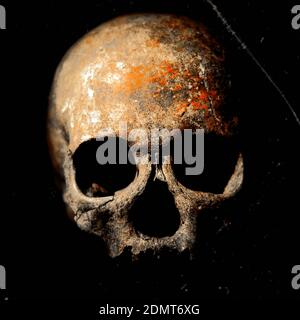 Dark scratched image of creepy skull with deep shadows in eye sockets on black background Stock Photo
