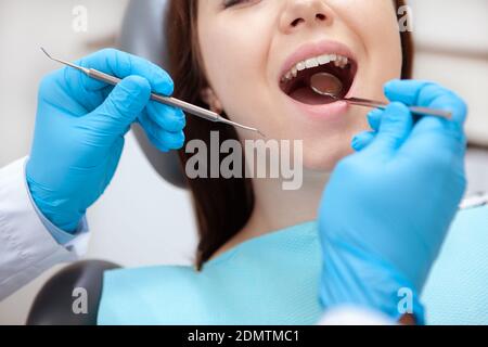 Cropped close up of a female patient with healthy teeth having dental examination by professional dentist Stock Photo