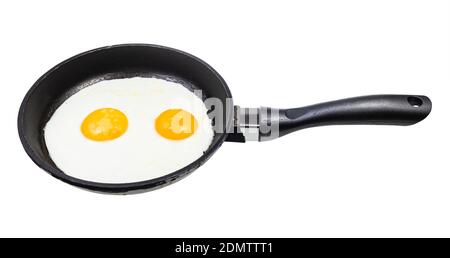 two fried eggs in black frying pan isolated on white background Stock Photo