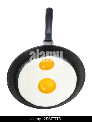 front view of two fried eggs in black frying pan isolated on white background Stock Photo