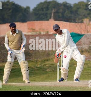 New Delhi India – March 3 2020 : Full length of cricketer playing on field during sunny day in local playground, Cricketer on the field in action, Pla Stock Photo