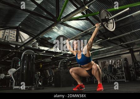 Focused on success. Low angle shot of an attractive strong muscular female bodybuilder doing heavy duty squats lifting barbell at the gym copyspace mo Stock Photo