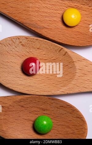 Wooden spoons on white background with red, yellow, green candy Stock Photo