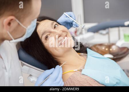 In good hands. Happy senior woman sitting in a dental chair smiling to her dentist during checkup at the dental clinic trust communication healthcare Stock Photo