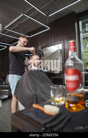 Vertical shot of a professional barber giving a new hairstyle to his male client Stock Photo