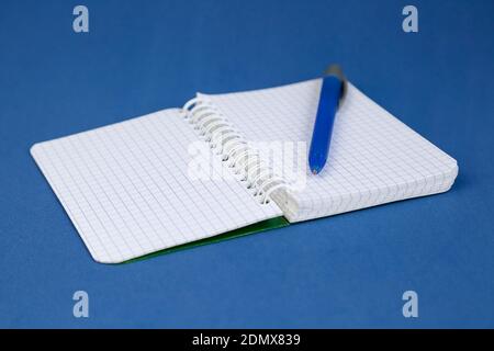 Open notepad and a pen on blue background. Writing concept. Stock Photo
