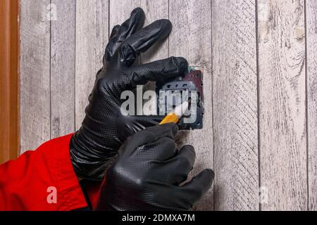 electrician installs an electric light switch on the wall Stock Photo