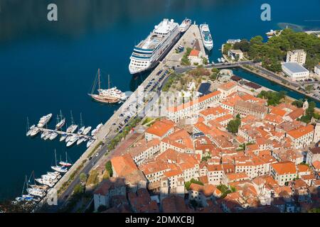 Kotor, Montenegro. View over the tiled rooftops of the Old Town from the city walls, the cruise ship Azamara Journey in port. Stock Photo