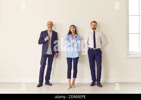 Portrait of standing in row smiling diverse team posing differently looking at camera. Stock Photo