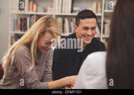 Happy college friends laughing joyfully, talking at the campus library. Cheerful male student having fun with his friends at school. Communication, li Stock Photo