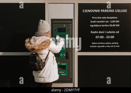 Sarajevo, Bosnia and Herzegovina - 12.16.2020: woman paying parking ticket on automated parking machine Stock Photo