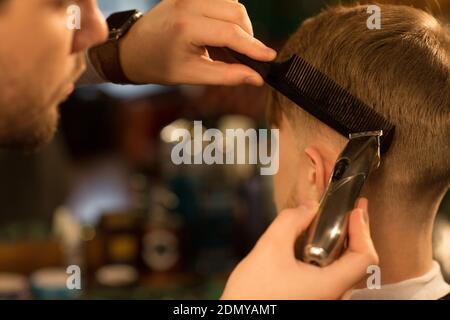 Close up cropped shot of a professional barber using comb and electric trimmer clipper gicing haircut to his male customer copyspace equipment barberi Stock Photo