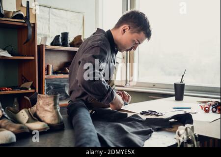 Manual production of shoes in the workshop the shoemaker begins with the preparation of a drawing from paper on the table. Stock Photo