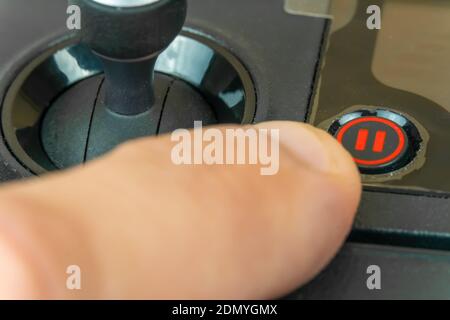 Man's hand presses the Pause button on the remote control of the drone. Stop. Stock Photo