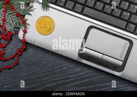 Composition notebook on the dark table with the bitcoin red beads , a sprig of Christmas tree with copy space, top view. Cryptocurrency Stock Photo