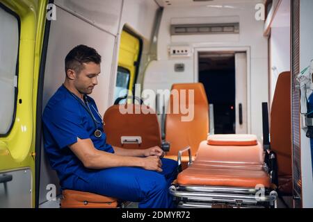 Tired and sad paramedic sitting in an ambulance car. Stock Photo