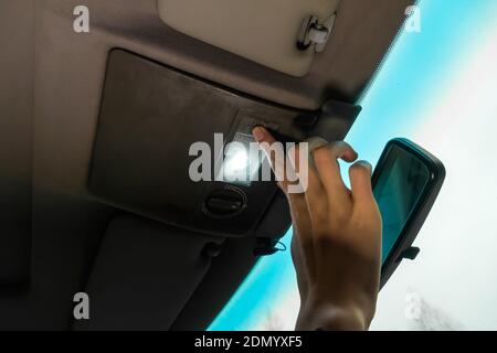 Woman's hand turns on the interior lighting in the car close-up Stock Photo