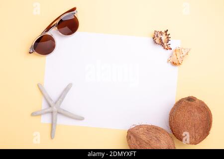 Blank paper, sunglasses, coconuts, seashells and starfish on yellow background. Concept of planning summer holidays and vacation - Image Stock Photo