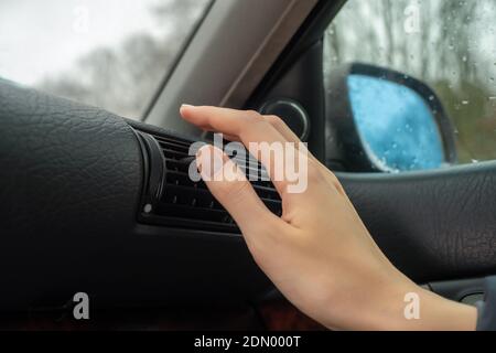 Woman's hand on the ventilation grate of an air conditioner in a car close-up. Climate control panel Stock Photo