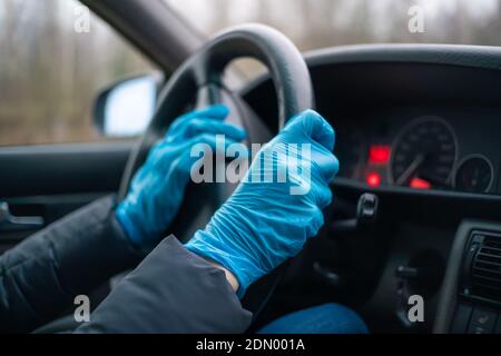 Hands of a female driver in blue gloves on the steering wheel of the car honking close-up. Concept of protection and prevention Stock Photo