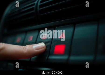 Woman's finger presses the emergency button highlighted in red on the instrument panel close up Stock Photo