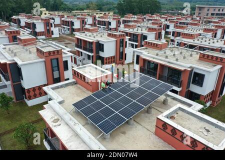 (201217) -- BAISHA, Dec. 17, 2020 (Xinhua) -- Workers install solar panels on roofs of new residence for people relocated from Gaofeng Village in Baisha Li Autonomous County in south China's Hainan Province, Dec. 11, 2020. Gaofeng Village sits in central part of the Yinggeling National Nature Reserve, almost isolated from the outer world due to poor condition of mountainous trails. More than 100 families in the village had been living in deep poverty before 2015 as many of them had no access to electricity, mobile telecommunication, and Internet services. They nearly had no alternative source Stock Photo