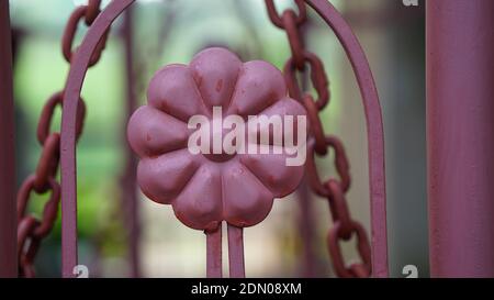 Modern stylish pink colored iron enter gate view with blurred background. Fashionable gate with round design. Stock Photo