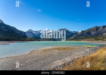 Barrier Lake Dam lakeshore in autumn season sunny day morning. Snow capped mountains in with blue sky in the background. kananaskis, Alberta, Canada. Stock Photo