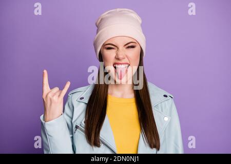 Closeup photo of good mood pretty lady sticking tongue out mouth teasing behavior crazy rocker showing horns wear casual hat blue modern jacket Stock Photo