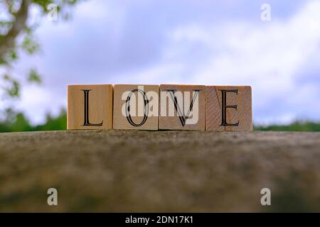 Love text on wooden block on top of big stone with blue sky background Stock Photo