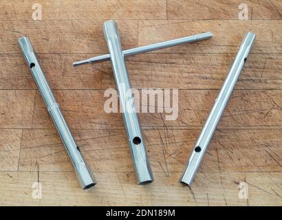 A set of three metric tubular or box spanners with a sliding or tommy bar against a wooden background. Stock Photo