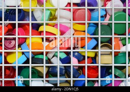 Collection of colorful plastic bottle Caps in a metal grid container for recycling Stock Photo