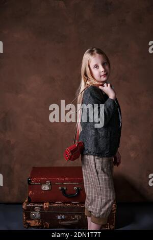 retro portrait of a little girl in a jacket with a leather camera case. studio. brown background Stock Photo