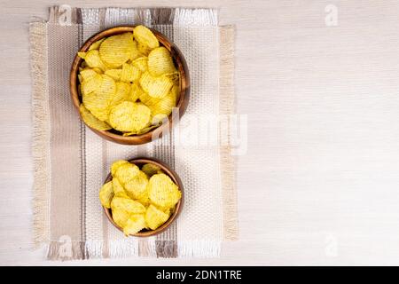 Fluted potato chips on a wooden bowl. small and large bowls, top view. copyspace Stock Photo