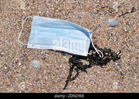 Face mask discarded on the beach Stock Photo