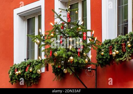 Christmas tree hanging in front of white windows on a red house wall in medieval town of Rothenburg ob der Tauber, Bavaria, Germany Stock Photo